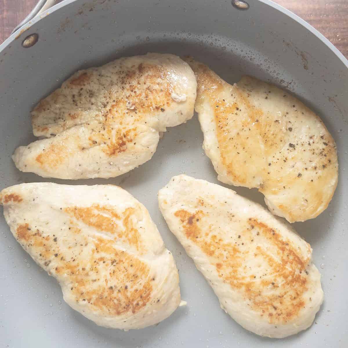 golden brown fried chicken breasts in skillet