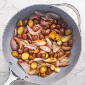 Browned baby red potatoes and shallots in skillet