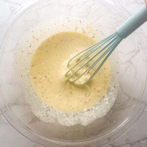 Eggs and ricotta cheese in a mixing bowl with a whisk