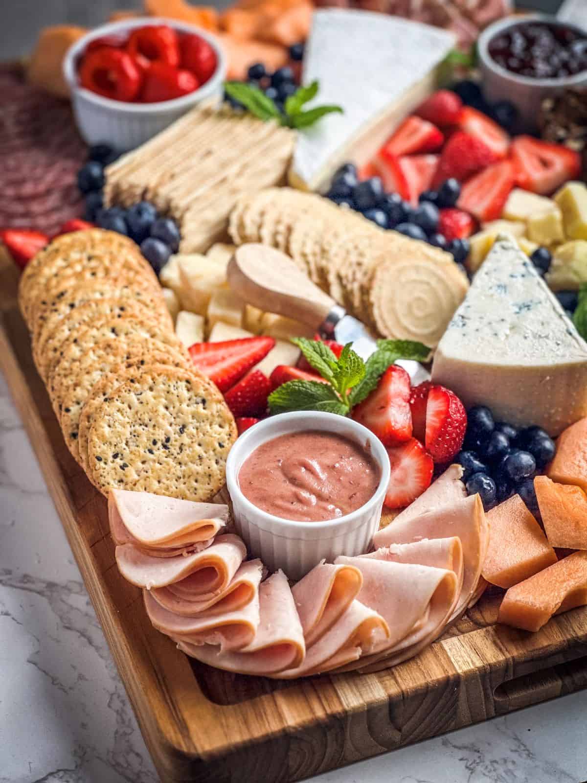 Charcuterie board spread with meats, cheese, fruit and crackers.