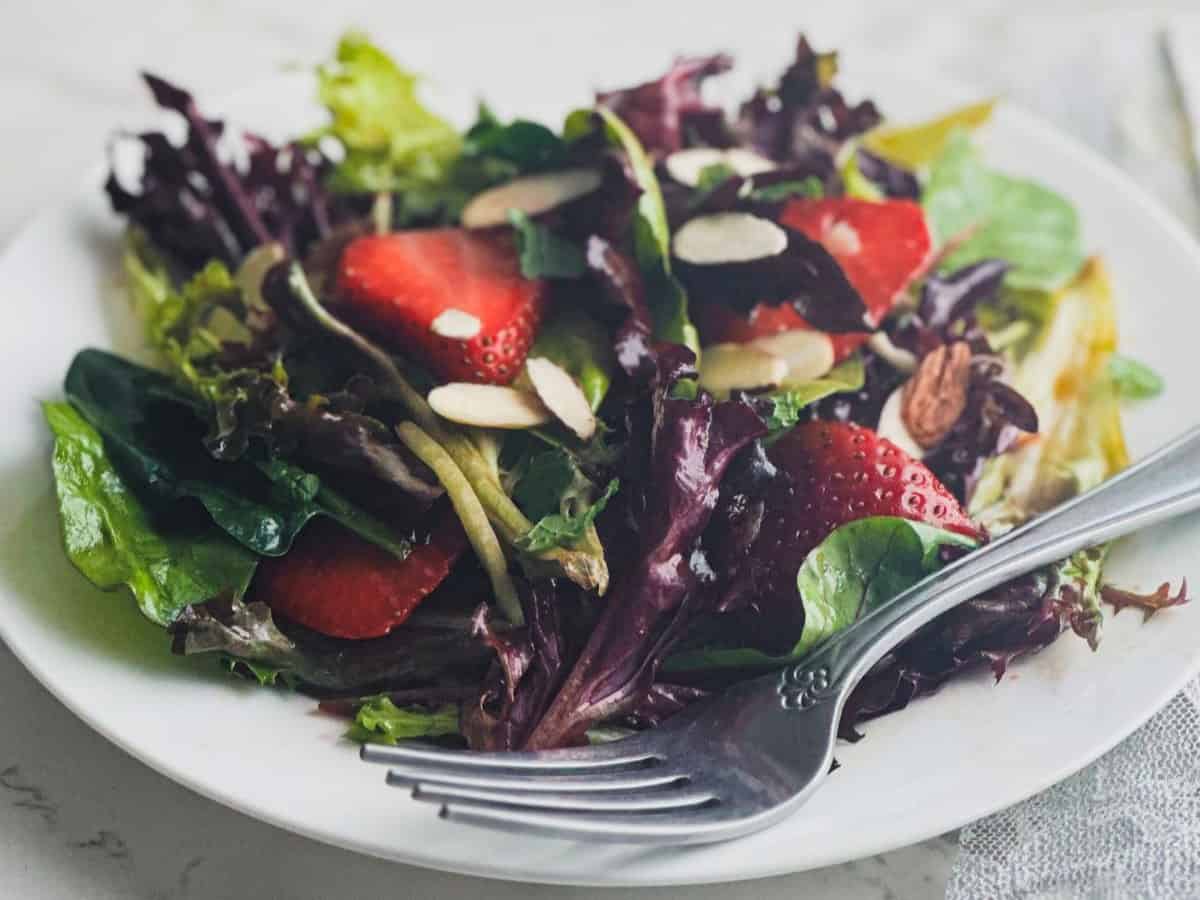 Strawberry spring mix salad on a plate with almonds.