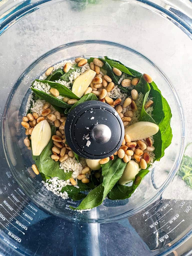 Basil pesto ingredients in the bowl of a food processor.