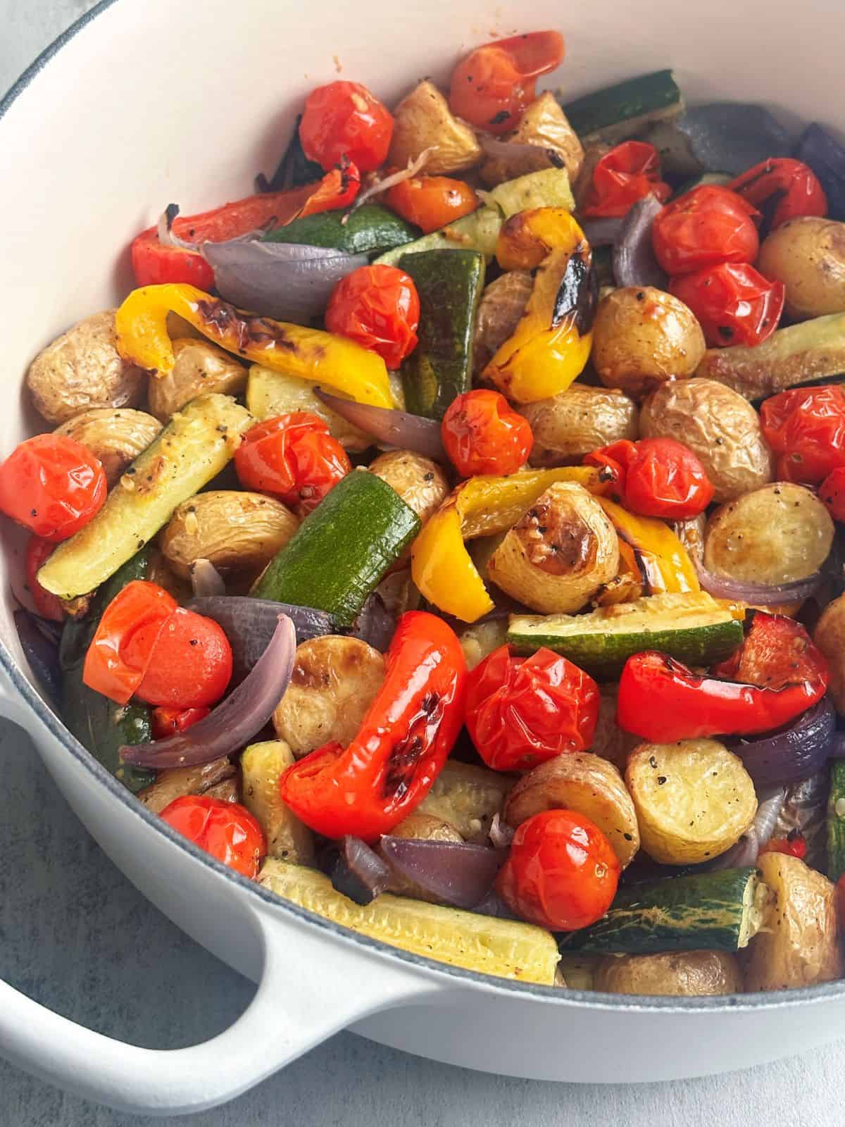 Roasted zucchini, potatoes, red onion, bell pepper, and cherry tomatoes in a pan.
