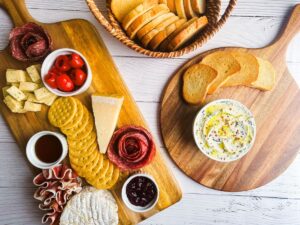 Wooden charcuterie boards with small dishes, cheeses, meats, and crackers.