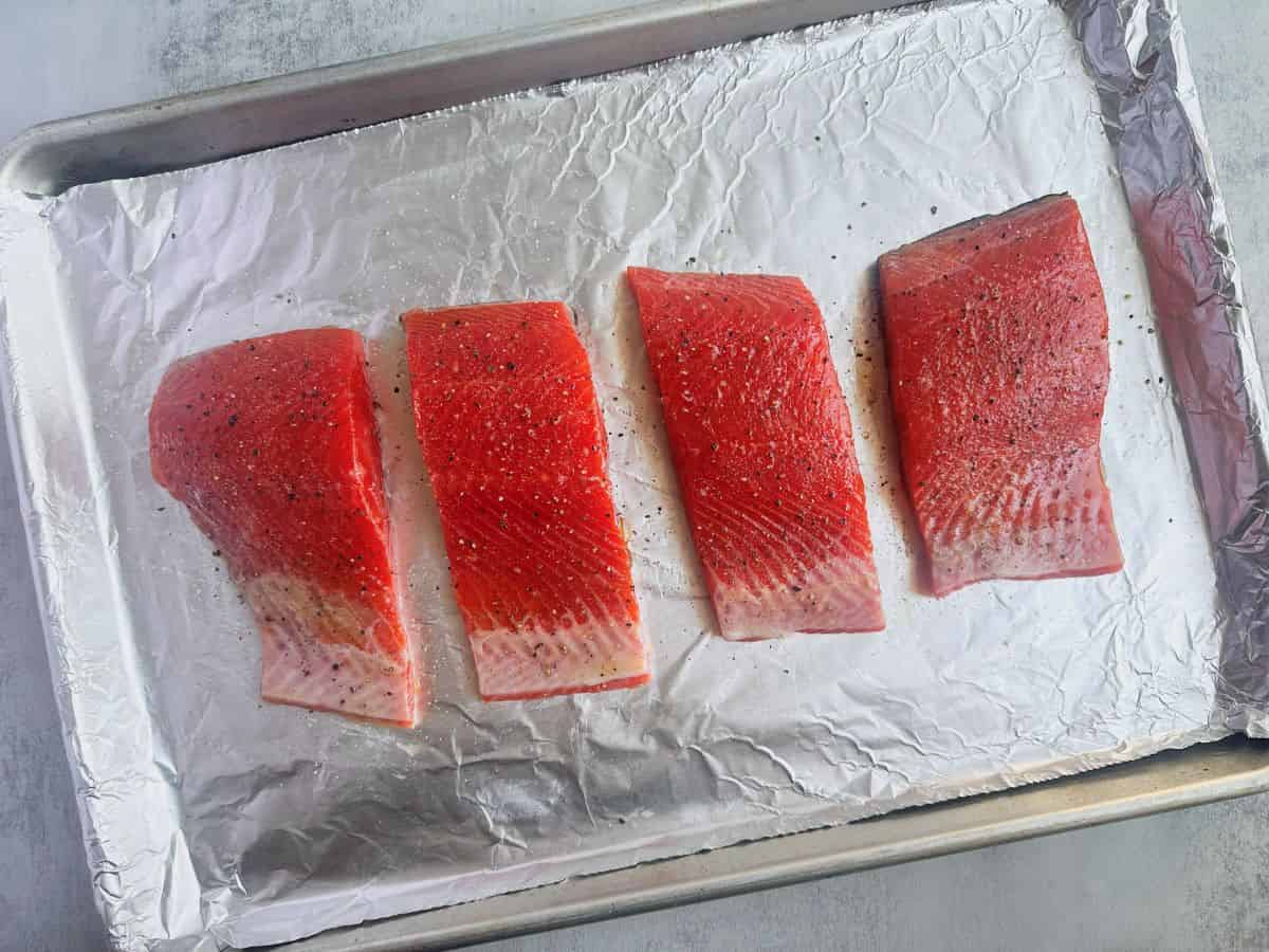 Sockeye salmon fillets on a baking sheet lined with foil.
