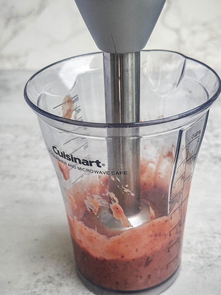 Cranberry honey mustard sauce in a mixer cup with an immersion blender.
