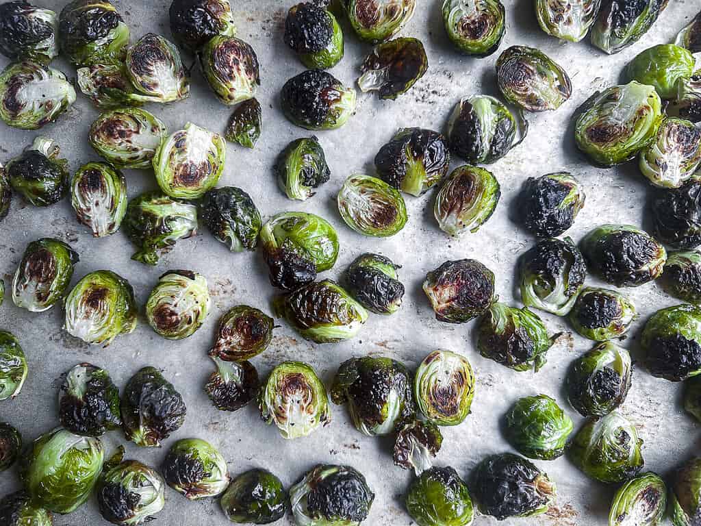 Roasted Brussels sprouts on a parchment lined baking sheet.