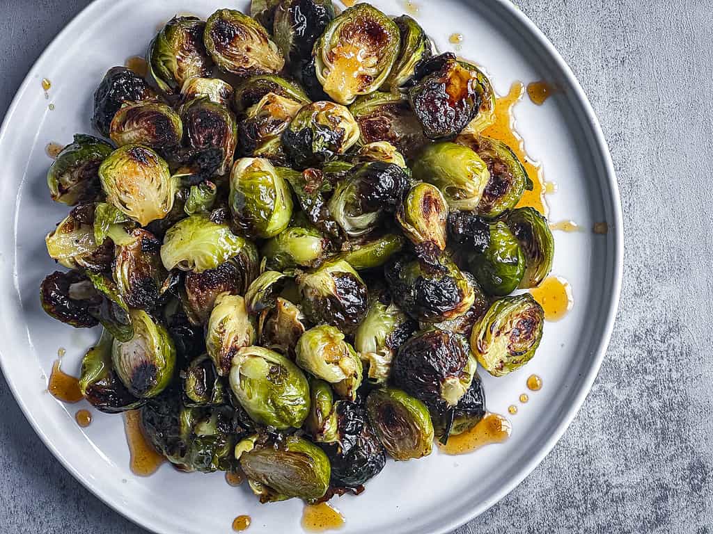 Roasted Brussels sprouts with maple sriracha glaze on a white plate.
