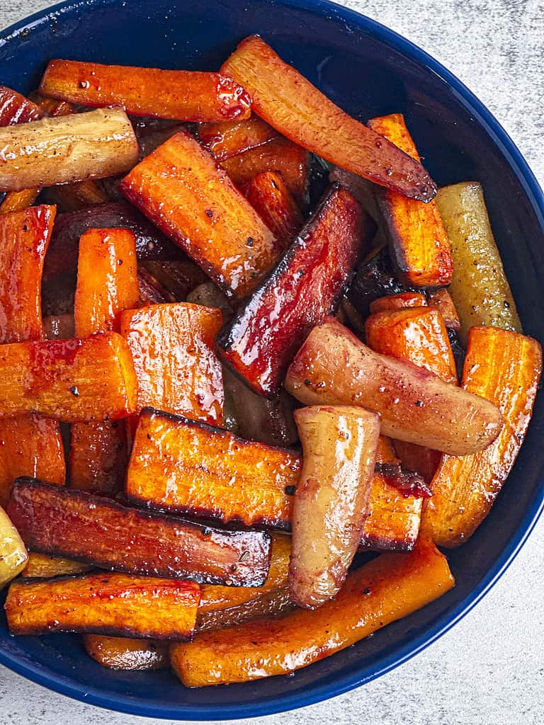 Spice roasted hot honey carrots in a dark blue bowl.
