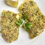 Two fillets of lemon herb crusted cod on a white plate with forks on the side.