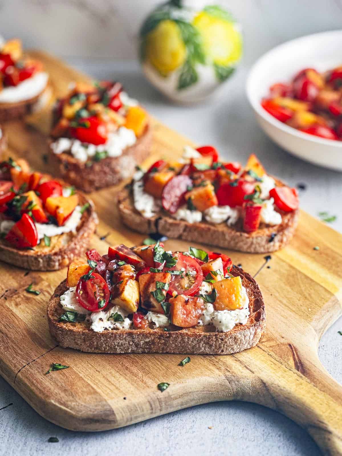Peach and tomato bruschetta on toasted bread with fresh burrata cheese.