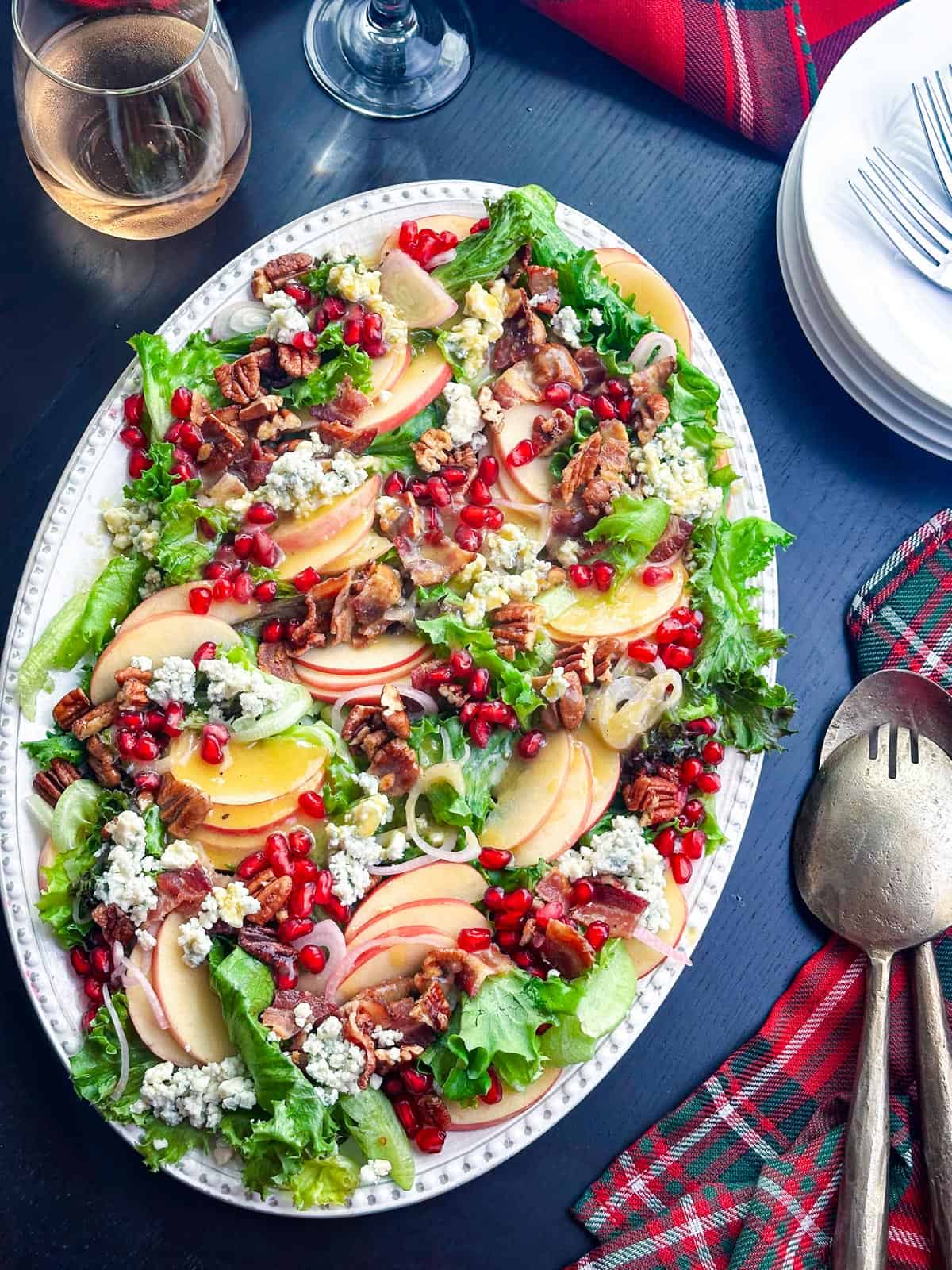 Fresh fall apple salad with blue cheese crumbles, candied pecans, and pomegranate seeds on a decorative platter.