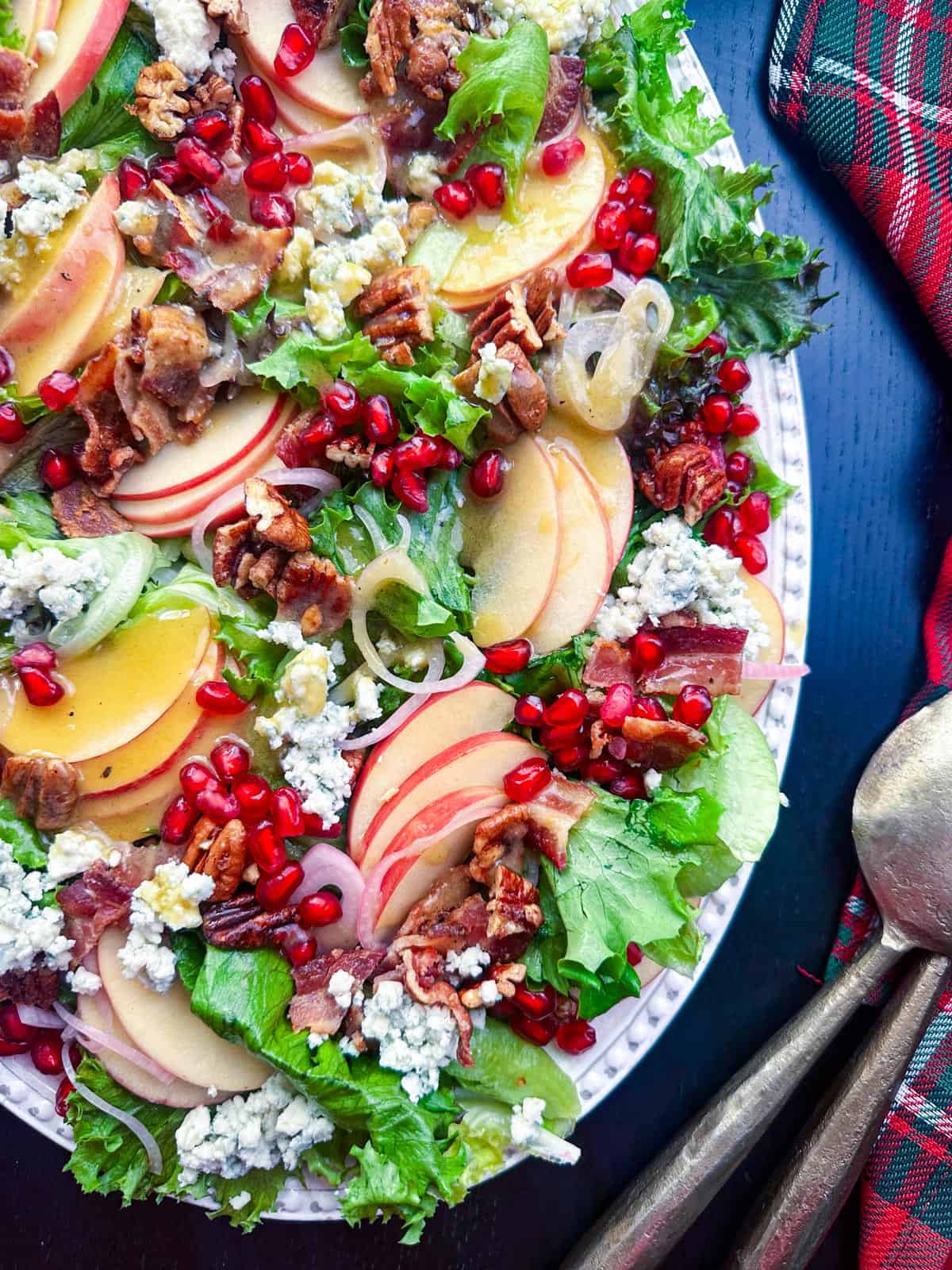 Fresh fall apple pecan salad with blue cheese and pomegranate seeds on a white platter.