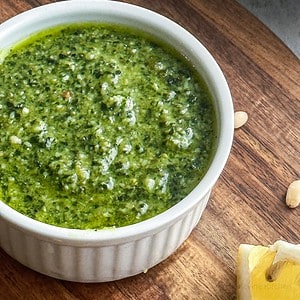Silky basil pesto sauce in ramekin on wooden surface