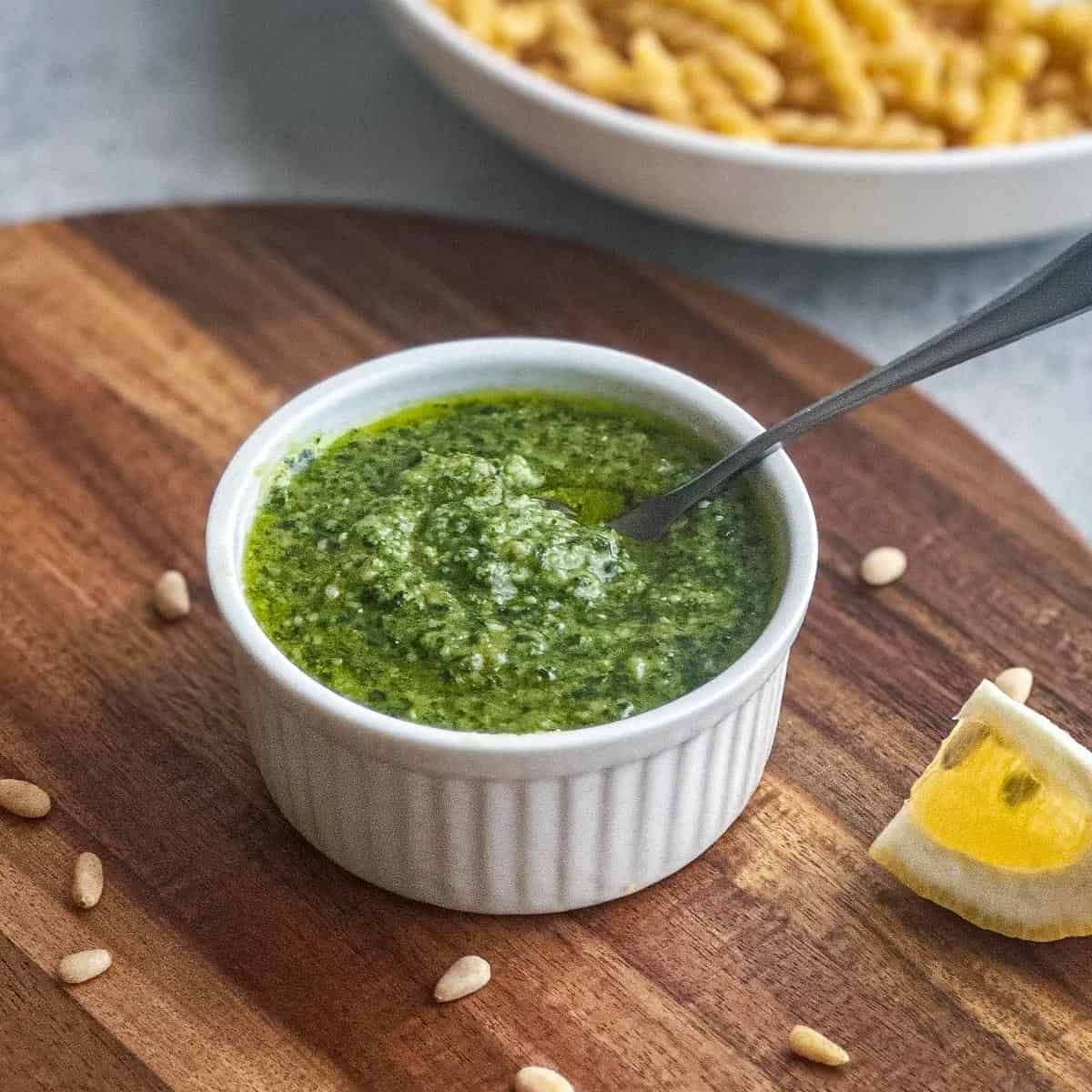 Basil pesto in a white ramekin with a spoon.