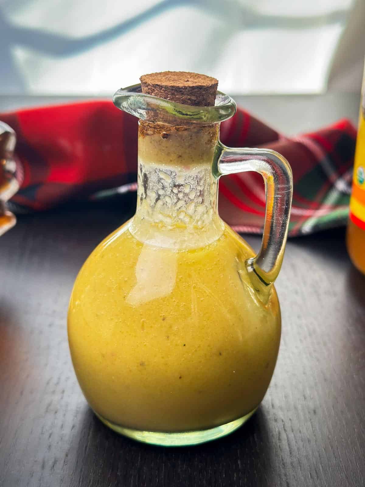 Apple cider salad dressing in a glass cruet with a cork stopper, perfect for enhancing recipes.