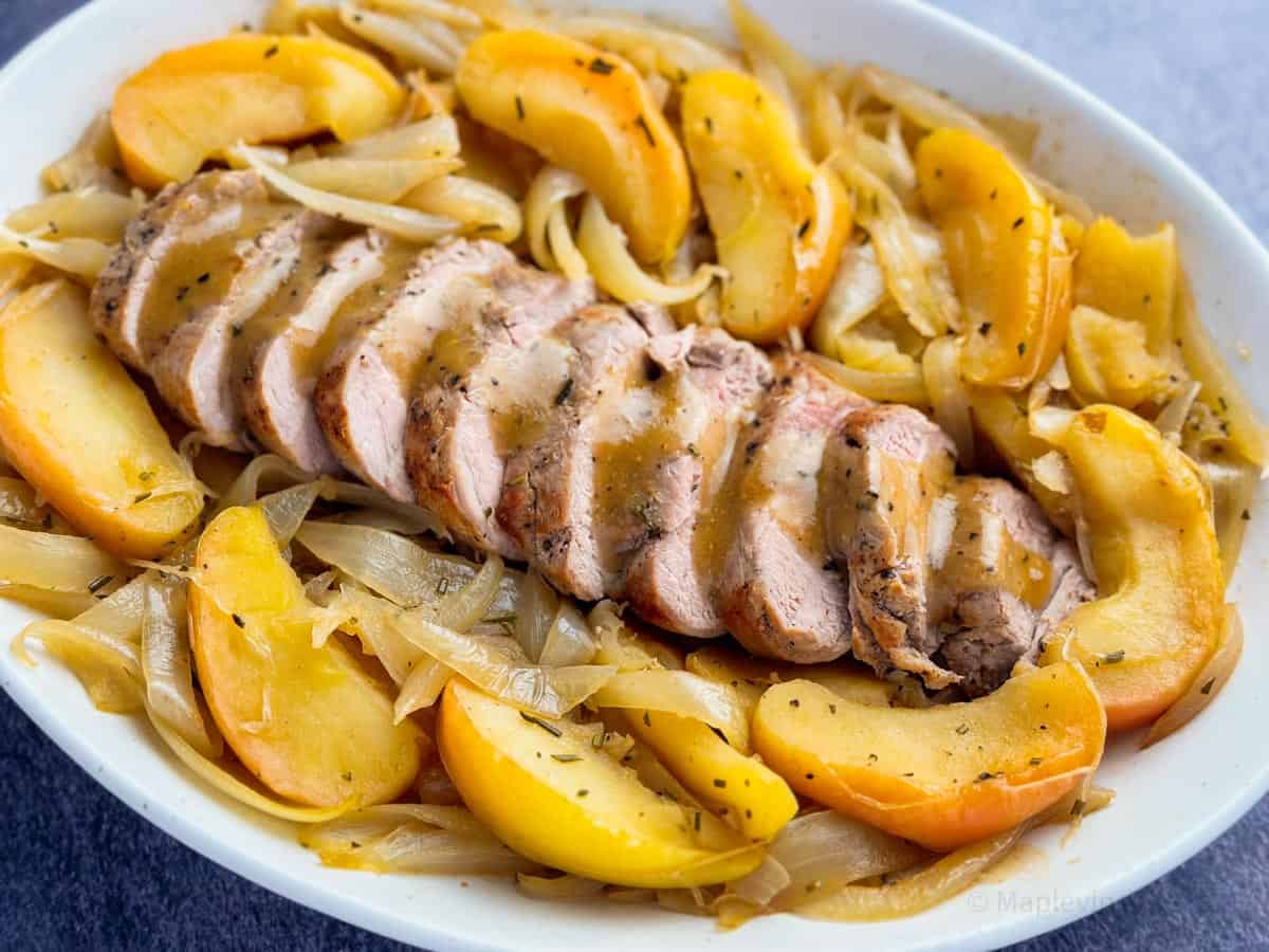 Sliced pork tenderloin plated with roasted apples and caramelized onions.
