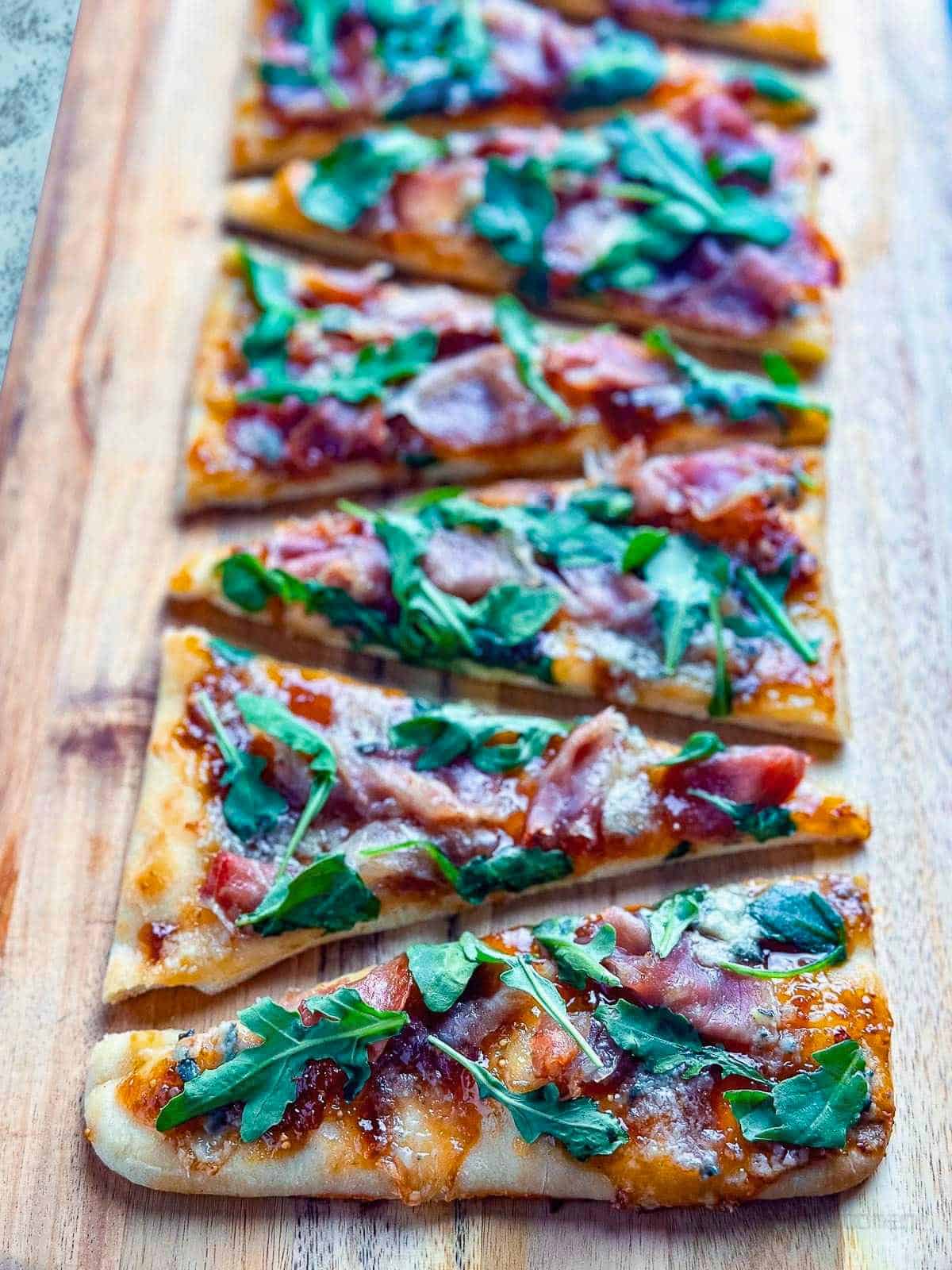 Delicious homemade flatbread pizza topped with fig jam, prosciutto, blue cheese, and fresh arugula.